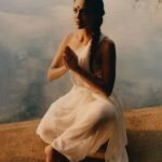 Rukmini Vijayakumar Instagram - “Once I enter the imaginative sphere, the world falls apart leaving the dewy grass, the moist leaves of the overhanging tree, the rays of sunlight escaping between the foliage of trees, and the silhouetted form of shiva in the distance to remain. I’m overwhelmed as he moves to adjust his matted locks over his shoulder… his sharp nose etched into the skyline behind. I can’t take my eyes off of him…. He looks my way and I turn away… am I shy? “ Photo @suleikamueller Styling @aartthie Featured in @vogueindia #parvati #shiva #srishti #imagination #performer #bharatanatyam #shivapurana #indiantradition