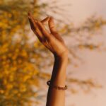 Rukmini Vijayakumar Instagram - “Once I enter the imaginative sphere, the world falls apart leaving the dewy grass, the moist leaves of the overhanging tree, the rays of sunlight escaping between the foliage of trees, and the silhouetted form of shiva in the distance to remain. I’m overwhelmed as he moves to adjust his matted locks over his shoulder… his sharp nose etched into the skyline behind. I can’t take my eyes off of him…. He looks my way and I turn away… am I shy? “ Photo @suleikamueller Styling @aartthie Featured in @vogueindia #parvati #shiva #srishti #imagination #performer #bharatanatyam #shivapurana #indiantradition