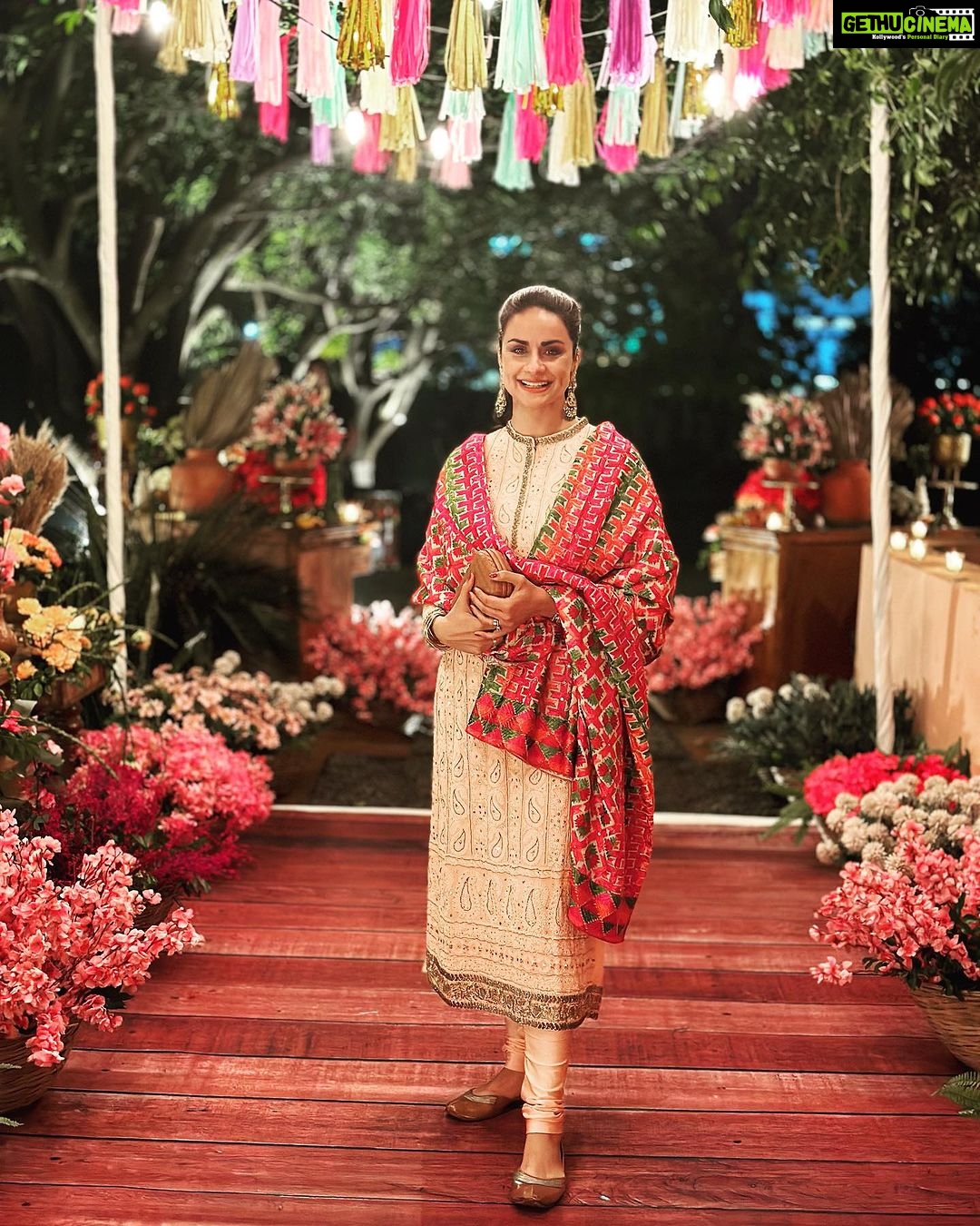 Gul Panag Instagram - The phulkari is such an integral part of our culture. From all things auspicious to all things festive -the phulkari is always there. Either as the main act. Or the supporting one, where we simply carry it on our forearms ( in addition to the full outfit and its own dupatta). At every wedding, shagan, engagement and jaago- the phulkari will ALWAYS make an appearance. Here I’m wearing a bagh ( all over embroidery) from @1469original . Occasion is Vatana. And my outfit is borrowed from @simranpotnis - we’ve decided to have all our clothes in JV now. 😅 Blue sari is @ritukumarhq . From 1999. Qualifies as vintage I suppose Also, managed to get HIM to pose for a picture.😅 @keeratkular thanks for the photos. And for reminding me that the knot clutch exists in my wardrobe. And of course for EVERYTHING else.😂 P.S Phulkari (ਫੁਲਕਾਰੀ) refers to the folk embroidery of the Punjab. Although Phulkari means floral work, the designs include not only flowers but also cover motifs and geometrical shapes. Incidentally, culturally prevalent in Punjab, Pakistan too.