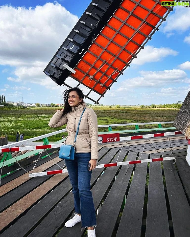 Niyati Joshi Instagram - Cold and crazy wind makes you forget FASHION 😂 It's all about SURVIVING the blustery wind. That's a windmill fan blade in the background in a Dutch country side village called ZAANSE SCHANS ,famous for its wooden windmills . #zaanseschans #amsterdam #europe #countryside #actor #niyatijoshi Zaanse Schans- A Windmill Village