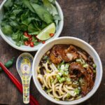 Adam Liaw Instagram - Tonight’s dinner. Braised wagyu tendon udon with Vietnamese herbs. I know you won’t believe me but this probably took 10 minutes of active time to make. Beef tendon braised in the braising liquid I used for soy sauce chicken and had in the freezer (see my post from about 2 months ago or on my website) with extra anise, tangerine peel, and black cardamom. Then the liquid diluted and seasoned to make a broth. The tendon braised using an off-heat method - bringing it to the boil the turning it off and letting it sit. I did the 4 times over the course of the day and it meant I never had to watch the pot. Just boil, switch off the heat and walk away. Perfect for when you’re in and out of the house all day like I was. Frozen udon (it’s the best udon you can get for home cooking), then served with lime, chilli and herbs.