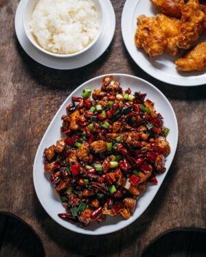 Adam Liaw Instagram - Tonight’s dinner. Gong bao ji ding (宫保鸡丁). A classic dish of Sichuan cuisine, but one that’s also been largely “lost in translation” creating so many misconceptions about Chinese cuisine outside China. 

It’s chicken flash fried with dried chillies, Sichuan peppercorns, spring onion and peanuts and within China it’s distinctive for (a) its seasoning profile of ma-la (hot and numbing) combined with sweet and sour, (b) being made with chicken breast, (c) and the inclusion of peanuts. 

It’s adaptations of “kungpao chicken”, “General Tso’s chicken” and “chicken with cashew nuts” largely remove the spice, replacing the dried chillies with capsicum and omitting Sichuan peppercorns, leaning more into a thick sweet and sour sauce, and use various nuts from almonds to cashews. 

It’s popularity, particularly in the US, has meant that  many people’s idea of a stir-fry is chicken breast, coated in a sweet and sour sauce with a lot of vegetables, and some nuts sprinkled in at the end “for crunch”, despite there being very few Chinese stir-fried dishes that do any of these things. 

So next time you see someone sprinkling sesame seeds over stir-fry, know that this dish is what started that kind of stuff.