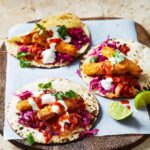 Adam Liaw Instagram – Fish finger tacos in the Taco Tuesday chapter of “7 Days of Dinner”. The fish fingers are frozen but the salsa roja is homemade and surprisingly simple – just grill some tomatoes and blend with the other ingredients.