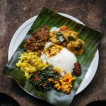 Adam Liaw Instagram - Yesterday I posted a picture of rendang, but I think it’s important to give those kinds of dishes context. I almost never make rendang on its own. It’s usually a celebratory food so there are plenty of other dishes that go around it like this plate of nasi kandar (or banana leaf). To make a meal like that takes a bit of balancing. Rendang the way I make it is rich, heavy, a little spicy (though not overly so) and kind of bittersweet in its taste profile. It would be overwhelming to have a meal of just that, so balance that I will always make something sweet and sour, in this case pickled Xinjiang chillies. There’s also a sour wild barramundi and okra curry. A mild dish of cabbage fried with turmeric and mustard seeds, a strongly savoury and fragrant kangkung belacan and there was also some fried chicken wings, and deep fried slices of bitter gourd and eggplant for both the texture and bitterness (not pictured). Each of these dishes brings something to the overall meal that combines for something much greater than each individual part.   It doesn’t get the same lens passed over it, but I think preparing a meal like this is as sophisticated an intricate as Japanese kaiseki or formal Chinese banqueting. In kaiseki the “rules” combine ingredients from the mountains, seas and forests cooked in different styles from steamed to fried to grilled. Chinese banqueting will follow mild dishes with stronger ones, steamed with fried etc. in the pursuit of balance. It’s all the same process of balancing that goes into preparing a good meal. I really think I should write a book about it because it’s something prevalent in almost all Asian cuisines, but not often discussed when those cuisines make it to the West.