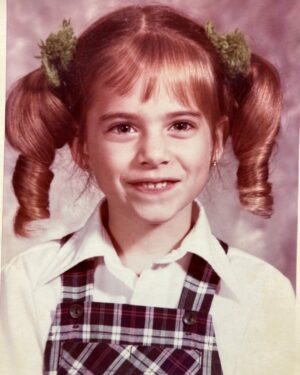 Amy Bailey Instagram - Fun fact: the night before my kindergarten photo I found some fingernail scissors and trimmed my own fringe (bangs 🇺🇸) into a really cool diagonal shape. ↘️
Only a 5 year old could rock up to a photoshoot with that whole hairdo, (vomit green pom-poms included) thinking, yeah I’m looking preettty cute rn.