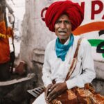 Arjun Kamath Instagram - Throughout my 11-year journey of photography, one thing has been a constant. I absolutely love street photography, clicking portraits in particular. Since the day I held a camera for the first time, I have been fascinated with faces & characters, along with the colourful surprises that lay scattered for me in every corner. And till date, I feel the same electrifying enthusiasm whenever I head out to capture the essence of Indian streets & its people, always trying to showcase their character & stories through my images. One such gleeful moment came about for me in the fruit market of Paithan, Maharashtra. It was a busy day on the streets &I was navigating through carts decorated with vibrant fruits when I saw this man. These days, you don’t easily find people wearing ethnic attire on the regular, so when I saw his bright red turban, I was instantly fascinated. At the time, he was buying apples from a lady, but amidst the frenzy, I could not find the right frame to click. So, I followed him as he left the apple cart, waiting for the right moment to take a picture. Soon, as he took a seat, I walked up to the corner & clicked the shutter button on my camera, capturing his curious gaze. I could tell from his expressions that he must have encountered a DSLR very few times in his life, and I was glad to have frozen that sweet moment in time. Furthermore, I have always been drawn to frames where the expressions of my subject are organic & raw, which I was able to capture here untarnished since the man barely saw me approaching. Right after, the moment I put my camera down, he greeted me with the warmest smile & joined hands to convey a Namaste. I smiled back at the warmth in his simple gesture. As I walked away, I thought to myself how this is the beauty of travelling in India, where I get to meet all these friendly strangers who always leave their mark. So many times have I been greeted with genuine smiles, wishes of a happy journey, and sweet goodbyes, that even in a strange land, I end up feeling at home. And I couldn’t be happier about it. #CapturedOnCanon with a Canon EOS 5D Mark IV & a Canon EF 24-70mm F/2.8 II USM Standard Zoom Lens #arjunkamathphotography