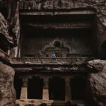 Arjun Kamath Instagram - I was recently in Aurangabad with mum and dad, where we made the unmissable trip to the marvellous caves of Ellora. A cluster of 34 caves dedicated to several religions and showcasing different architectural styles, the place was an enigma that unfurled slowly. This particular picture is of Cave 10, a majestic Buddhist monastery cum cathedral that left me awestruck in a single gaze. It was a sunny afternoon and I was walking around in admiration of the archaic beauty all around me, when I came across this stunning facade. Instantly, I froze at the splendour of it all, and it didn’t take me two seconds to find the perfect frame that I wanted to shoot. Knowing that my parents had already ventured inside the cave, I decided to sit down on the damp ground without any care in the world. I was curiously waiting for them to wander into the balcony at some point, all set to freeze the moment. As soon as my father stepped in, I waited for the tourists to move away and requested him to walk to the edge of the balcony. Watching him stand there wearing a contrasting blue against the rustic brown cave, I felt like a child who had been surprised with candy and thus couldn’t hold his excitement. Dad lingered there for a while and then carried on since it was sweltering hot. But it was time enough for me to get the shot, almost as if my muscle memory had taken over, scouting the perfect composition and then clicking the shutter button on my camera. And although I rarely share wide shots of my travel stories, my eyes are accustomed to see the world in terms of stories and enticing frames. So, whenever I see one, I can’t help but take a photograph. This time around, the moment was all the more special, since I had the pleasure of having someone from my family grace the frame, adding a personal connection to it. #CapturedOnCanon with a Canon EOS 5D Mark IV & a Canon EF 24-70mm F/2.8 II USM Standard Zoom Lens #arjunkamathphotography #dad #elloracaves #india #DoGreatWithCanon #MentorsInFocus #EOSMaestro Ellora Caves, Aurangabad