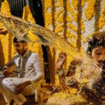 Arjun Kamath Instagram - The Haldi festivities of Sreethika and Ranadeep kicked off at The Wildflower in Medchal, with the sun shining bright and the beautiful yellow decorations popping against the greenery. It was a lovely sight to see! The happy couple fully embraced the Haldi festivities, with their family members applying Haldi to their faces one by one. Laughter filled the air, occasionally accompanied by a refreshing spray of cool water, as the sun rose in a golden hue. Watching the beautiful ceremony, I couldn't help but smile at the bright colours and joyful laughter. However, my attention was diverted when Sreethika's friend suddenly appeared and playfully splashed water onto her face like a mischievous wizard! Sreethika was utterly shocked and surprised by the sudden splash of saffron water. As her giggly friend rushed over with the water pot, startling Sreethika into a scream, I remained focused on the moment. Reacting quickly, I captured the delightful moment in seconds, preserving it for eternity. I must confess that I appreciate candid pictures as they capture genuine moments that posed shots often lack. The essential element of a photo is to convey the emotions of the moment rather than just aiming for a flawless pose. Even if they're not perfect, candid photos can evoke cherished memories that we hold dear. Ultimately, a picture without emotion is like a rainbow with only one colour. Sreethika & Ranadeep, Hyderabad- Dec ‘22 @canonindia_official @srishtidigilife #bride #haldi #haldiceremony #yellow #sunrise #water #splash #emotions #wedding #weddingphotography #weddingdecoration #telugubride #DoGreatWithCanon #MentorsInFocus #EOSMaestro #instagram #arjunkamathphotography Medchal, Hyderbad