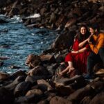 Arjun Kamath Instagram – Love is like the ocean— calm, playful, fierce, and beautiful all at once. ✨

An already magnificent Goa was all the more mirthful when one fine morning, I found myself ambling its crystal blue shores. Up above, the sun was preparing to glide from plump silver clouds. Whereas beneath my feet, the soft earth pressed and swelled with each poised step I took. In these soothing moments of dawn, I was accompanied by Pragnya and Hemanth, a joyful couple who had tied the knot recently. 

As we ambled on the beach, their laughter and conversation filled the salty air with melodious chimes. And everywhere we looked, the sheer glory of life greeted us with open arms. A glimmering horizon, the fleeting company of birds, the lone boat passing by all made for a gorgeous story, and I was thoroughly delighted to find myself in it. 

It was during these tender moments that I noticed Hemanth and Pragnya lost in conversation, reveling in each others’ company. And so, as they sat curled up by the earthy rocks, the sun began to show up in a fanfare of bright pinks and reds in the sky. 

Admiring the frame, I decided not to steer too close to the couple and simply freeze this golden moment of love from afar. As I clicked the shutter button on my camera, it was as if the waves of warmth and love had found their way into my heart. I could not help but wish that I could remember this moment for a long, long time.

Pragnya & Hemanth, Goa, 2022 

#arjunkamathphotography #preweddingshoot #photography #sunrise #prewedding #preweddingphotography #photoshoot #coupleshoot #goa #DoGreatWithCanon #MentorsInFocus #EOSMaestro #instagood #instagram