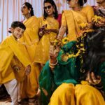Arjun Kamath Instagram - Memories from a day when the sun came down to play with us. 💛 Nidhi's glorious wedding ceremony was preceded by the most jovial and colourful haldi celebration. The morning was still young and fresh at the Heritage Khirasara Palace of Rajkot. The family was painted in a bright and inciting yellow for the haldi, bringing the scene to life with a riot of colours and celebration. As I walked the vibrant space, I was glad to observe the mirth that filled the air along with all the sparkle and gold. The ladies sang folk songs and danced in circles, the kids played catch in all their liveliness, and Nidhi, laced in grace and charm, was taking in each precious moment as felicity unfurled around her. To my delight, these pictures reflect the pure joy that filled the room that morning. Each moment bursted with colour and energy, and I was grateful to revel in its glory as I froze those precious emotions in time. Today, when I see these photographs, I can't help but transport myself back to that sprightly morning and feel the bliss I felt then all over again. Nidhi+Shirish, February 2022 #CapturedOnCanon with a @canonindia_official EOS R5 with a CanonRF 24-70 f/2.8 L USM #weddinng #weddingphotography #weddingphotographer #weddingflowers #haldiceremony #haldi #indianwedding #arjunkamathphotography #rajkot #DoGreatWithCanon #MentorsInFocus #EOSMaestro #instagood #instagram