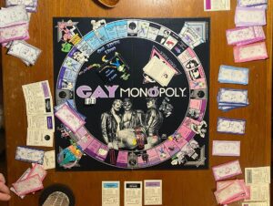 Augustus Prew Instagram - Playing Gay Monopoly on Fire Island with some of my chosen family is truly what life is all about and exactly what nature intended. Thank you Weather Queen for honoring our games night with a dramatic storm, it added the chicest snuggliest backdrop to our games night. Love ya girl.
Quick bit of history- Gay Monopoly was an unofficial tongue in cheek version of monopoly developed by “The Parker Sisters”- truly some of the wittiest writers of all time (see “You were caught eating quiche”card) in 1983 to raise money to fund AIDS research which at the time was already devastating the gay community and which very little was being done to prevent by the (straight) powers that be (google Larry Kramer/Eric Sawyer/Anthony Fauci). You could buy it in stores and everything until Parker Brothers (owners of the actual monopoly game) sued them for copyright infringement because a)they are homophobic capitalists (ironic also given that the game was initially created to warn against capitalism) and b) they are boring (see Straight City photo to understand that reference). It’s now a really rare gem of a game so if you have/find one, look after it with all your heart and keep it close because it has immense historic significance. My favorite part of the game is the “Do you know your queer history?” card, where if you land on it have to answer a question about influential queer people throughout history- I learned about George Washington Carver, HansChristian Andersen and Benjamin Britten and was reminded of the passage in the Bible that tells us that King David loved his boyfriend Jonathan “surpassing the love of a woman” in the book of Samuel. Yes that’s actually in the Bible so you can keep that one for your next holiday season. Oh and the Benjamin Britten was gay. Didn’t know that either. Playing it amongst the ghosts of Fire Island (many many many queer people died of AIDS here- most had nowhere else to go) and a mere block from the house of Patient Zero (the first known person to be infected by the HIV virus) was profound to say the least. I love y’all. Look after after each other. Queer people are so powerful. We always have been and we always will be 😘🌈❤️