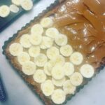 Chrissie Swan Instagram - At the behest of @s.j.talbot and many, many others… behold my Banoffee Pie recipe! What you’ll need: 1 packet McVitties Digestive biscuits. 100grams melted butter 1 tin condensed milk. 3 bananas 400ml cream, whipped with 2 tablespoons of caster sugar and slurp of vanilla extract. Makes it taste like vanilla icecream 🤤 Dark chocolate (not much - just to grate on the top) HERE’S WHAT TO DO: Make the Dulce de leche. (You can buy a pre-made product called Caramel Top n Fill but I don’t like it anywhere near as much as the one I make below - reasonable shortcut though) Take label off a tin of condensed milk and place it in a saucepan full of water (leave the tin sealed). Make sure there’s a few centimetres of water above the top of the can (and I do about 5 at a time because this part takes the longest! They store in the fridge (sealed) forever and it means you can get a Banoffee on the table within minutes) Bring water to the boil then turn it down to a simmer, lid on, about 4-5 hours checking the water hasn’t evaporated. After that time I just leave it in the water to cool down (it takes hours). When it’s cool enough to open you have the most delicious caramel ever! BISCUIT BASE: Blitz the biccies then stir in the melted butter. Push into a greased pie dish or square quiche tin - whatever you like - and bake for just 5 minutes on about 180. Whack into the fridge for a few hours until properly cold. ASSEMBLE! Spread your caramel onto the biccie base, arrange sliced bananas, top with whipped cream. Use a micro plane to grate some chocolate on top! Scoff. ❤️ 🍌 🥧