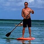 Craig Shoemaker Instagram - This might look so much cooler, making you think I’m X-Game Gary, taking on waves in the deep sea, if there wasn’t some sun-visored floating tourist on retirement vacation in the shot! On my way to Florida, off the standup board and back where I belong, on a standup stage. @visanidinnertheater Thurs-Sat. Don’t worry. I’ll wear a shirt. #aruba #keynotespeaker #tedxspeaker #coach #letmecoachyou #winningwithhumor #lovelifeagain #funnyismoney The Ritz-Carlton, Aruba