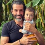 Gustavo Santos Instagram - SEIS MESES DE ANTÓNIO! SOU DAQUELES HOMENS QUE AMA SER PAI, PAI POR INTEIRO, E QUE COLOCA ESSE LUGAR COMO UMA PRIORIDADE EM TODAS AS HORAS DA SUA VIDA. "P" DE PRESENÇA. "A" DE AMOR. "I" DE INCONDICIONAL. SOU PRESENÇA DE AMOR INCONDICIONAL. EU, QUE ATÉ AOS 38 ANOS, NEM PENSAVA NISTO. TALVEZ ME ASSUSTASSEM A RESPONSABILIDADE, A FUGA DO TEMPO, AS FERIDAS QUE TAL COISA ME PODERIA REVELAR... MAS AQUI ESTOU EU, AOS 46 ANOS, COM MAIS UM PUTO NOS BRAÇOS E QUE CELEBRA HOJE MEIO ANO NA PELE. FELIZ, É COMO ME SINTO. AMO A RESPONSABILIDADE. AGIGANTA-ME. NÃO ME FALTA TEMPO NENHUM (SÓ PARA TRETAS QUE VALORIZAVA NA ALTURA E QUE, AGORA, QUANDO POSTAS NO OUTRO PRATO DA BALANÇA, NÃO VALEM ABSOLUTAMENTE NADA). SINTO-ME MAIS CENTRADO DO QUE NUNCA. E QUANTO ÀS FERIDAS DA MINHA INFÂNCIA, QUE APARECERAM MESMO, TENHO APRENDIDO A GOSTAR DE CONHECÊ-LAS E ME DESAFIADO A CURÁ-LAS SEM JULGAR QUEM MAS ABRIU. ESTOU MAIS LEVE, MUITO MAIS LEVE. TEM SIDO UMA VIAGEM INCRÍVEL... ... SOBRETUDO, DENTRO DE MIM; MAS CADA PALMO CONQUISTADO É, TAMBÉM, SORVIDO POR ELES. GANHAMOS TODOS! OBRIGADO FILHOS!