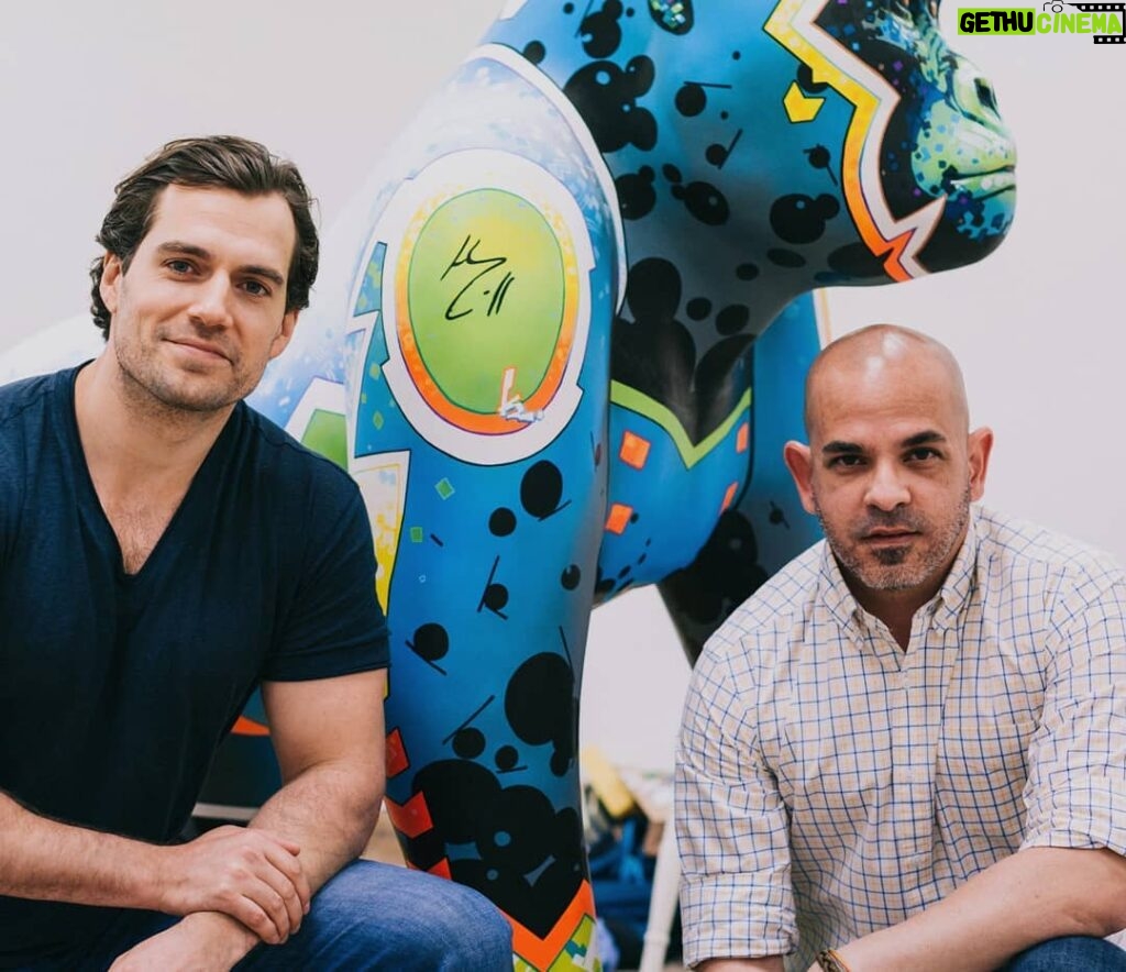 Henry Cavill Instagram - My fellow croucher in this photo is my friend Kenneth Rocafort! From comic book fame, no less! And that handome fellow behind us is one of 40 gorillas on Durrell's new Go Wild Gorilla Trail! This one was painted by the mighty Kenneth himself. However, many other artists also graced us with their talents to paint the Gorillas that populate the Gorilla Trail which will guide visitors, and locals alike, around the island on a path of conservation enlightenment. Go Wild Gorillas' primary task is to raise funds so that they can build our family of Western Lowland Gorillas a new and even more fantastic home at Jersey Zoo. Find out more by following the link in my bio. Animal fact incoming: The Western Lowland Gorilla is one of a group of animals that has a triplet of a name in Latin. Which is divided into Genus, Species and Subspecies it is quite simply Gorilla Gorilla Gorilla. Boom. Knowledge. Go forth. #GoWildGorillas @GoWildGorillas @Durrell_JerseyZoo @mitografia_kr