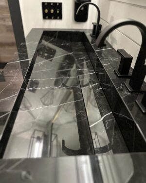 John Colaneri Instagram - New sink designed, installed, and ready to use! The first sink I designed at our home had some design issues. Live and learn! This new sink by @faithfulcountertops is absolutely fire 🔥 ! Changed it up to a black porcelain that looks like marble but without the maintenance.  Thoughts on the design and how do you think we access the drain. 

#design #designinspiration #designgoals #surfacedesign #porcelain

Faucets by @brizofaucet