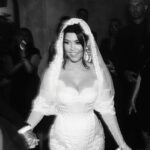 Kourtney Kardashian Barker Instagram - One year ago, we had our first in-person meeting with @dolcegabbana to start the design process of my wedding dress!! The first inspiration for my dress was when Travis and I were watching Guns N’ Roses November Rain video one night before we were even engaged, and we said to each other “this has to be our wedding.” She was wearing a short dress and I thought to myself “I need a short dress!” I had more visions inspired by some 1990s campaigns of Monica Bellucci shot by Helmut Newton for Blumarine. When we knew our wedding was going to be in Portofino, it also influenced the vibes and feeling of the dress. I also just wanted to feel like we ran off to Italy and got married and wanted the dress and wedding to feel that way! When @dolcegabbana suggested putting Travis’s head tattoo of the Virgin Mary on the handmade lace veil with the words from his tattoo: family, loyalty, respect underneath, I got chills and knew how special that felt. (And my little mini veil I wore to dinner ☺️) This was all planned and made into my dream come true all so so quickly and I’m so grateful to everyone who put their all into making it all happen! ✨🫶🏼❤️