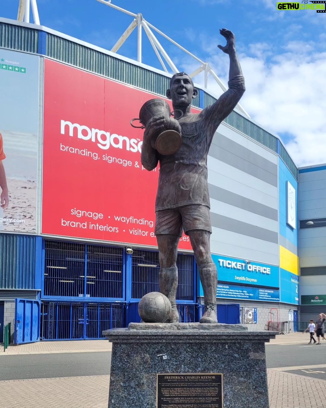 Mário Marra Instagram - Dia de #tbt é dia de lembrar do dia que conheci Cardiff e o Cardiff City. Mais distante da região central, ir para o estádio envolvia a operação erro zero para não perder o trem para Londres. Deu tudo certo e ainda ouvi várias músicas como If You Tolerate This Your Children Will Be Next, do Manic Street Preachers. Conhecer o Cardiff City é conhecer um pouco mais da história do único time de fora da Inglaterra que foi campeão da Copa da Inglaterra, a FA Cup. Logo na frente do estádio uma bela estátua de Fred Keenor, ídolo do clube e de todo País de Gales. O zagueiro e, desde cedo, líder do time esteve em campo na vitória de 1 a 0 sobre o Arsenal, em Wembley, na final da FA de 1926/27. Mas não foi só lá que ele esteve... Já titular do Cardiff e da seleção de base, Frederick Charles Keenor recebeu a convocação para fazer parte do chamado Football Battalion, regimento do exército inglês que lutou na Primeira Guerra Mundial. Fred Keenor teve ferimentos na perna esquerda durante a chamada Batalha de Somme, uma das mais sangrentas da Primeira Grande Guerra, e acabou ficando longe do futebol por um tempo, se recuperou a tempo de erguer a taça. O Cardiff não vive os seus melhores dias. O técnico é o turco Erol Bulut, ex-jogador do Fenerbahçe. O torcedor está na euforia de voltar a ter Ramsey como sua referência em campo, mas as aspirações são diferentes das daquela época, da época de Fred Keenor. #tbt #cardiffcity #wales #gales #manicstreetpreachers #keenor #championshipnaespn Cardiff City Stadium