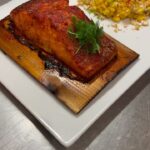 Michael Voltaggio Instagram - cedar planked salmon the technique of cooking salmon on Cedar goes way back as Native American tribes in the Pacific Northwest have been cooking Salmon on Western Red Cedar for centuries. retro by voltaggio @mandalaybay is all about going back in time. this preparation takes me back to my time working for chef Larry Forgione. I worked the fish station at American Place in New York under chef Forgione in 1998 and cooked hundreds of his version (yes I’m that old) This one is brined, coated in blackening spice and smothered in a smoked roe beurre blanc emulsion that can be heated to proper gravy smothering temperature without breaking. an off the cob elotes is served on the side. summer summer summer time…