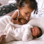 Parisa Fitz-Henley Instagram - I’ve been auntied again! 🙏🥹💓💓 Feeling so incredibly grateful for these two wonderful souls. Rumi St. Ledger Fitz-Henley was born a week ago. I got to witness the miracle of his entrance via indomitable, kind, loving mama @koolkelsey with @fitztheworldcitizen backing her up and rally driving to the hospital like a pro 🚗💨 . And it’s been such a heartwarming experience to see big sister Anaya Soleil giving him gentle pats and strokes, and looking to him in concern when he cries. Shout out to Grandma Kim and Mimi Sally, coming through with so much support and wisdom. Some blessings are just pure sweetness. 🙏💓✨ Image description: Two slides with minor differences. Close on two year old Anaya, doting on newborn Rumi, who lies on white sheets sleeping. He wears a white onesie with his hands covered, she wears a white tank (and her hands are still baby-squishy with little knuckle dimples 🥰). In the second photo Kelsey’s hand is barely visible touching Rumi, and Rumi is a little more tightly snuggling himself.