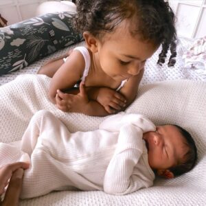 Parisa Fitz-Henley Instagram - I’ve been auntied again! 🙏🥹💓💓 Feeling so incredibly grateful for these two wonderful souls. Rumi St. Ledger Fitz-Henley was born a week ago. I got to witness the miracle of his entrance via indomitable, kind, loving mama @koolkelsey with @fitztheworldcitizen backing her up and rally driving to the hospital like a pro 🚗💨 . And it’s been such a heartwarming experience to see big sister Anaya Soleil giving him gentle pats and strokes, and looking to him in concern when he cries. Shout out to Grandma Kim and Mimi Sally, coming through with so much support and wisdom. Some blessings are just pure sweetness. 🙏💓✨ 

Image description: Two slides with minor differences. Close on two year old Anaya, doting on newborn Rumi, who lies on white sheets sleeping. He wears a white onesie with his hands covered, she wears a white tank (and her hands are still baby-squishy with little knuckle dimples 🥰). In the second photo Kelsey’s hand is barely visible touching Rumi, and Rumi is a little more tightly snuggling himself.