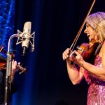 Rhonda Vincent Instagram – 🎧: @rhondavincent // @adamhaynes4 🎻🎻
📍: @industrialstrengthbluegrass 
📸:l @xlacimack 

#rhondavincent #fiddle #twinfiddles #bluegrassmusic #pinkdress #marthawhite Industrial Strength Bluegrass