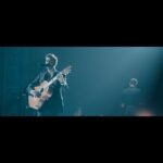 Tiago Bettencourt Instagram - Aqui fica um bocadinho da música inédita no novo álbum (já no youtube também). Chama-se 'Caminhar'. Fala de mares profundos e gostava que a recebessem com tempo e serenidade ✨. Tem uma desarmante orquestração da @ehsaraross, interpretada pela @orquestraclassicadocentro_occ, dirigida pelo @diogocosta.conductor. Nos coros estavam @mariana.norton, @claudiapascoal e a minha banda 🧑🏻‍🤝‍🧑🏻👬👬. Imagem realizado pelo @arlindocamachophoto ⚡ "Caminhar" Se for por medo o que não vês, fecha os olhos Há um mar sereno, uma voz que nos guia Há lado negro em todos nós, uma ferida Se for por medo o que não vês, não me olhes Vai no vento sem temer a descida Há um mar profundo em todos nós, uma ilha, onde em segredo todo o ar se expira Leva a força dos trovões - caminhar Leva gritos e orações - caminhar Esquece a perda e o rancor - caminhar E a tristeza, meu amor - caminhar ... Traz a força dos trovões, caminhar Traz os gritos e orações, caminhar Esquece a perda e o rancor, caminhar Alegria, meu amor. Se for sereno, o que lá vem, vou contigo Serei a pedra deste chão e abrigo. Coliseu dos Recreios