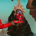 Vermelha Noir Instagram - 🩸 Chinnamasta 🩸 Es una diosa hindú que se representa desnuda auto-decapitada, normalmente en pie o sentada en una pareja divina copulando, sostiene su cabeza decapitada en una mano y una cimitarra en la otra. Tres chorros de sangre surgen de su cuello y son bebidos por la cabeza decapitada y dos asistentes. Es la diosa de las contradicciones. Simboliza ambos aspectos de Devi: la que da y la que quita la vida. Es considerada tanto un símbolo de autocontrol sexual como una personificación de la energía sexual, dependiendo de la interpretación. Representa la muerte, la temporalidad y la destrucción así como la vida, la inmortalidad y la recreación. Para este trabajo en colaboración con @dankografia y @jesusteayude cuento con la presencia de ellos mismos como la pareja copulando y a mi hijo @bendeck_bendeck y @lvbnagaia cómo las entidades a los lados de la diosa. . Fotografía y dirección C @dankografia @jesusteayude Dress & heels: La presi y Makeup, headpiece & styling: Vermelha Noir . 💄 PRODUCTOS 💄 ⚪Base : Labial Rojo MAC Cruella 👁️ Ojos y contour : @jeffreestarcosmetics ⚫Delineador y cejas @guerlain 🖤 Labios @naturalgirl ⬛ Enmarcado @bodypaintbykj . #fashion #drag #gay#art #makeup #lgbt #photograph #instagay #dragqueen #instadrag #dragrace#lgbtq #queen #dragmakeup #instagay #dragqueyensoyfinstagram #gayboy #dragqueenmakeup #fashion #fashiondesigner #makeupartist #style #art #localqueen #dragartist #red #secondhandclothing India : इंडिया