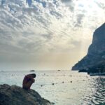 Beatriz Costa Instagram - Último post sobre a viagem que não é bem sobre a viagem. Temos uma sequência de fotografias em que parece que estou a ser abraçada pelo sol - ali a rasgar as nuvens para me agarrar; e depois temos uma das coisas que mais me impressionou no museu do vaticano: uma pintura do Dalí que mostra como a leveza e a alegria, quando dançam, deixam a angústia des-mai-ada (ela ali no canto a derreter numa pedra). É basicamente isso. Tudo neste post é sobre leveza e alegria, não vemos a angústia, porque ela estava fraquinha e decidiu não aparecer. A última (também numa das paredes do vaticano) parece-me um anjo a tentar mostrar a um mortal onde é que está a luz, mas ele não está a perceber nada, só olha para as asas. Achei bonito e ilustrativo. Mas se calhar sou só eu que estou a ver coisas. Beijo-vos anonas do deserto, boa noite 🤍 Italy