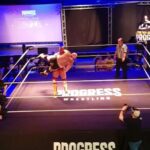 Brian Button Instagram - Hater/Troll: "Well, I could throw Darby Allin around like that too. That's not that impressive." Cage: Hold my protein shake while I throw this 300 lbs of @damomackle over my head. #machine #swolverine #progress #aew #bodyguy #strongboi