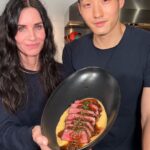 Courteney Cox Instagram - He should do this for a living Steak Au Poivre + Creamy Polenta Ingredients Steak: 8 oz Zabuton Steak 1 whole Garlic 3 sprigs Rosemary 5 sprigs Thyme 4 tbsp Butter 1/4 cup Yondu Umami Sauce 1 tsp minced Chives Au Poivre Sauce 1/3 cup Cognac 1/2 cup Beef Jus  1/2 cup Heavy Cream 2 tbsp Crushed Peppercorn 2 tbsp Green Peppercorn 2 minced Shallots 2 tbsp Butter Creamy Polenta 2 cups Coarse Polenta 4 cups Chicken Stock 1/2 cup Dried Porcini Mushrooms 2 cups Heavy Cream 3 sprigs Rosemary 3 sprigs Thyme Instructions: Pre-heat oven to 220F. Season your steaks with kosher salt.  Get a carbon steel/cast-iron pan ripping hot, add any high smoke-point oil, and once smoking sear steaks on all sides until brown then remove from pan.  Drop heat to medium, and add butter, garlic, thyme, and rosemary.  Once foaming, return steaks, and baste all sides until browned further, about 30 seconds a side.  Remove steaks again, add your Yondu umami sauce, then pour over steaks.  Place into oven and cook to desired doneness, ours were cooked to 132F.   Add your chicken stock, polenta, and dried porcini mushrooms to a pot and get boiling.  Make sure to whisk continuously.  Once simmering, lower heat and continue whisking every five minutes.  In a separate pot make infused cream.  Add heavy cream, rosemary, and thyme.  Polenta should be finished after 45-60 mins.  Add the infused cream to polenta at the end and adjust seasoning to your liking. To make the sauce, melt your butter in a pan and sweat the shallots until soft, about 3-5 minutes.  Add your cognac off the heat, being careful as flareups can occur.  Reduce the cognac until almost gone, about 90%, then add your beef jus and heavy cream.  Add your green and black peppercorns and simmer until you get a gravy-like consistency.  Adjust seasoning.