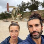 Emily Baldoni Instagram - On this #earthday we decided to take a morning hike. We thought these photos sum up the heartbreak of what we are doing to our planet. Just behind a gorgeous lookout lies a hideous oil well. Forcefully penetrating the earth and taking from it over and over again. If you look closely behind us you’ll also notice that the trees have black bark on them. Slowly recovering from the devastating #thomasfire a few years ago. This year in Southern California we are seeing unprecedented low levels of rain which is terrifying for coming fire season which the local fire department told us yesterday now lasts pretty much all year. And unfortunately, these are just a few examples of how we are knowingly continuing to destroy our beautiful home. If we want to have anything left of our planet to give to our children and grandchildren, we must work together and listen to the 97% of scientists who remind us that climate change is real. It’s not a hoax or some government conspiracy. It’s caused by us, but the good news is that it can also be fixed by us. Much of the damage can’t be undone, but we DO hold the power to reverse a lot of it. First we must come together and acknowledge the role we ALL play in it. #earthday #onlyoneplanet #onepeople