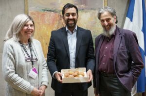 Humza Yousaf Instagram - Thanks to Ephraim and Margalit from the Scottish Council of Jewish Communities for bringing Giffnock's finest sufganiyah to @scotparl today, as #Hanukkah, the Jewish Festival of Lights, gets underway.

A reminder, in spite of the darkness of recent times, of the power of light and of hope.

Chag urim sameach!