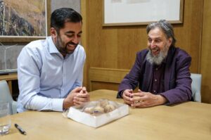 Humza Yousaf Instagram - Thanks to Ephraim and Margalit from the Scottish Council of Jewish Communities for bringing Giffnock's finest sufganiyah to @scotparl today, as #Hanukkah, the Jewish Festival of Lights, gets underway.

A reminder, in spite of the darkness of recent times, of the power of light and of hope.

Chag urim sameach!