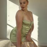 Iskra Lawrence Instagram - Mama is off to Miami this weekend for a bachelorette with 16 baddies… it’s about to be carnage🥵 until 11pm because - bedtime. so it’ll be sensible carnage and lots of reading books on the beach🫠 Photo description #accessibility : [Iskra is statuesque standing against her wall with golden hour sunlight pouring through the windows on her glowing skin. Wearing a mint green satin mini dress, with a clear gold Perspex handbag and gold strappy stiletto heels embodying the slayage] Miami, Florida