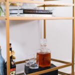 Jasmine Davis Instagram - The hubby and I are trying to spend less money out grabbing a drink and more time saying “aht aht” we got drinks at home. This @ashleyofficial bar cart fits our aesthetic perfectly and provides just the right amount of space for his “spirit’s collection”. Nestled flawlessly in our living room, the bar cart completes our space and makes hosting a breeze. #myashleyhome #ashleypartner