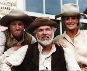 Linda Evans Instagram - I absolutely loved working with Kenny Rogers – it was memorable for a million reasons. He was one of the great ones – kind, thoughtful, dear… the best of men. 
Many of you know that I love pizza so much, that if you wake me up in the middle of the night and ask me if I’d like a slice, I’ll say YES. Kenny used to have it delivered to me while we filmed The Gambler. 
When I “sang” with Kenny, he assured me that no matter how I sounded, they could fix me in the studio. I trusted him completely. He was such an incredible singer and songwriter. But the truth be known, even though I would be dubbed, I still had to perform the song. I’ll never forget those moments as I belted out, way off-key, while Kenny stayed in character, holding a straight face, and all I could feel was his love. 
He was a remarkably good man who brought music into all our lives, and his unforgettable voice and beautiful heart will live on in mine. 💛🎶🌟