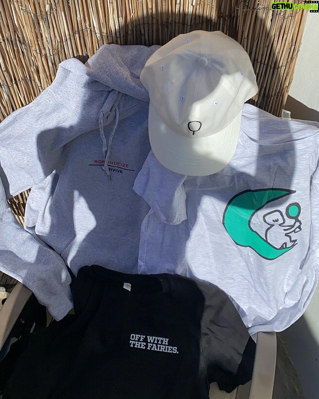 Maddie Phillips Instagram - I have been secretly designing my own merch line and today i set her free !!! the seeds for this expansion were planted as an 11yr old when i would design ~soft angst funny sk8er grl~ clothes (and took it VERY seriously lol) under the pseudo name Anarkid (which would then become my personal company name). 16 years later i found myself for the first time in years, (despite many wonderful new blessings in my life) not being able to feel my feet on the ground & with no clear vision. I started experiencing panic attacks like Iβd never known until I one day when my body was simply too EXHAUSTED to freak out again, I had the sudden awareness that i was aching to create tangible expression and literally the day after I articulated in my mind that I would honor my desires and somehow delve into that realm, I received a dm from Frank @sunshineshop.la asking if I had ever thought about creating my own merch line. lmao :β) indeed I had. π I drew the little mirror holding moon-being 6 years ago during a significant era of reflection and itβs been on my bedroom wall ever since. i am no illustrator however !!! the fairies/dancing muses are the works of two talented artists who were able to conjure up my creative visions. i will be so tickled to see what resonates with you all !! but i must say β¦ heheβ¦ i am so utterly fulfilled by this entire experience already and am truly releasing this with such joyful detachment because; the best thing about it all is the reminder that when introspection & participation start to reach for each otherβs hands and begin to dance, doors are revealed and your expanded selves greet you with beaming faces and open arms and exclaim βWE FUCKING KNEW IT !!! WELCOME HOME BABY!!!!!β Thank you Frank my friend @sunshineshop.la for opening the door π πͺπͺπ link in bio πͺπͺπ artist collaborators !!! @alsor.studio (OWTF) @jhen.ai ( π§ ) 22222