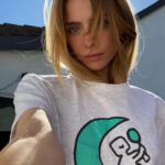 Maddie Phillips Instagram - I have been secretly designing my own merch line and today i set her free !!! the seeds for this expansion were planted as an 11yr old when i would design ~soft angst funny sk8er grl~ clothes (and took it VERY seriously lol) under the pseudo name Anarkid (which would then become my personal company name). 16 years later i found myself for the first time in years, (despite many wonderful new blessings in my life) not being able to feel my feet on the ground & with no clear vision. I started experiencing panic attacks like I’d never known until I one day when my body was simply too EXHAUSTED to freak out again, I had the sudden awareness that i was aching to create tangible expression and literally the day after I articulated in my mind that I would honor my desires and somehow delve into that realm, I received a dm from Frank @sunshineshop.la asking if I had ever thought about creating my own merch line. lmao :’) indeed I had. 🌙 I drew the little mirror holding moon-being 6 years ago during a significant era of reflection and it’s been on my bedroom wall ever since. i am no illustrator however !!! the fairies/dancing muses are the works of two talented artists who were able to conjure up my creative visions. i will be so tickled to see what resonates with you all !! but i must say … hehe… i am so utterly fulfilled by this entire experience already and am truly releasing this with such joyful detachment because; the best thing about it all is the reminder that when introspection & participation start to reach for each other’s hands and begin to dance, doors are revealed and your expanded selves greet you with beaming faces and open arms and exclaim “WE FUCKING KNEW IT !!! WELCOME HOME BABY!!!!!” Thank you Frank my friend @sunshineshop.la for opening the door 💛 🪞🪄🌙 link in bio 🪞🪄🌙 artist collaborators !!! @alsor.studio (OWTF) @jhen.ai ( 🧚 ) 22222