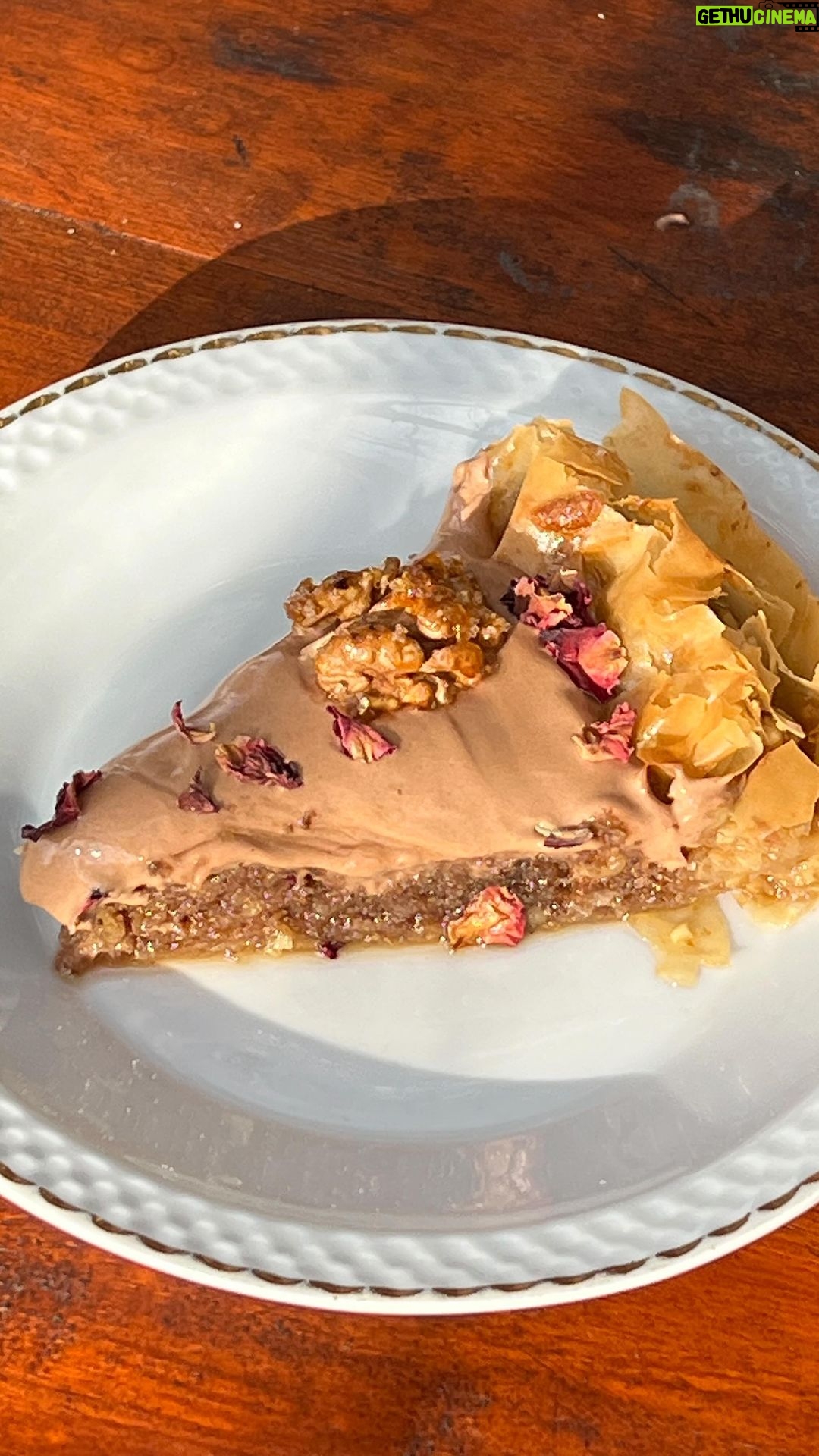 Maria Jekova Instagram - Спомени от отминали дни, преплетени с вкуса на настоящия живот. Какво значи за мен зима по мой вкус? По един начин свързвам зимата с празниците, каквато е и тази рецепта - отново извадена от дълбините на съзнанието ми, там, където са най-милите спомени. Направете празниците тази година по ваш вкус - както ще ви доставят радост на вас, сладост и спокойствие - пак на вас. Без суетене, без тревоги от очаквания. Като цяло това послание може да бъде извадено от контекста на зимата и да си пожелаем по-често да живеем по наш вкус. По-често, да не кажа - винаги. Това ще бъде и моето пожелание към вас, към тази новогодишна рецепта, която споделям с вас, вдъхновена от Jameson Black Barrel. Много хора си мислят, че обгарянето на бъчвите дава пиперлив аромат и вкус на уискито, а всъщност то задълбочава, подслажда и карамелизира вкусовете и уханията, като ги прави съвършени за съчетание с десерти, а и в такива. Ако това е моята зима, то Jameson Black Barrel те кани да създадеш зима по твой вкус, като тази година те раздават и награди, изрисувани от българския артист Борис Праматаров. Повече информация ще намерите на jbbwinter.com. А сега към рецептата на моята зима. Четири слоя фини точени кори се редят във форма за тарт, а между тях смлени орехи и масло. Два фитила с пълнеж от орехи се навиват и се засукват като обръч около ръба на формата - както съм показала във видеото - те ще задържат плънката в центъра. Изпича се за 5 минути, сякаш печем маслена основа за тарт. След това правим орехов кекс, който разстиламе в средата. Смесваме първо: 3 жълтъка, 50 грама кафява захар, 100 грама смлени орехи и 100 грама ръжено брашно, 10 грама бакпулвер, щипка сол и 50 мл Jameson Black Barrel. Разбиваме 3 белтъка на сняг и ги влагаме накрая. Печем за 10 минути на 180 градуса. Оставяме да изстине, като през това време правим сироп от 500 грама кафява захар, 3 резена лимон, 100 мл розова вода, 100 мл Jameson Black Barrel и 400 мл вода. Заливаме студената баклава с горещия сироп. Накрая правим крем от една кофичка заквасена сметана, 150 грама мармалад от шипки с петмез и 50 мл Jameson Black Barrel. Завършваме с карамелизирани орехи и сушени венчелистчета от цвят на шипка.