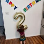 Mary Katharine Ham Instagram - This gal turned two! For those keeping count, that means we had two under two… for 9.5 months. And we’re still standing! A lot of the credit for that goes to Holly, who much like her father, has a GIANT personality and also loves a schedule. That means she sleeps. Hallelujah, can that girl sleep, from 6pm-7am, in the same room as her brother. When we say “bedtime for baby?” after two episodes of “Bluey,” our girl marches herself up the stairs to get her zzzzs. “Bye, guys! Bye, guys! Bye, Guggy!” (this is either doggie or Garnet, we’re not sure which) She is a woman of few words. She says “Dad” constantly, “wow” and “Scout” and “stop” and “don’t,” usually to her bro. She has a long-running joke where I ask her to say “Mama,” and she mouths it without actually saying anything and then laughs because, let’s face it, that’s funny. But she resorts to “Mama” when she’s very sad, which isn’t often. She is good-natured and very physical. The other day, I told her to say “please,” and I would lift her over the couch, and she was stubborn about “please” and simply hoisted herself over the couch with a ridiculous display of brute upper body strength. She is newly into books, but her brute strength makes her the first kid I’ve ever had capable of destroying board books. She might be the most problem-solving kid I’ve had. She untied, collapsed and removed the tent pole from her little play tent in the living room while I wasn’t looking the other day, then uncollapsed it to hold up in front of me. (Meanwhile, her brother is already saying “bottle” in an effort to defend himself against her when she steals his bottle, which is often). Watching her play is a bit like watching the velociraptors test the fences. “Clever girl.” She loves to clean (also gets that from Dad), brings her own diapers for diaper changes and throws the dirty ones away. She’s just started doing “big hugs” and will hug you and sigh and pat you on the back. Sings along with “Daniel Tiger” and loves cheese, ham, and anything I’m eating. She has made a lot of our lives possible the last 9 months by just being her and, boy, do we love her! Can’t wait to see her grow!