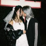 Nadezhda Tolokonnikova Instagram - 💍🔪🫀 american boy уеду с тобой @voguemagazine 📝: Sewing used to be a source of trauma for Pussy Riot’s Nadya Tolokonnikova, who was forced to stitch military and police uniforms while in a Russian penal colony. But she decided to reclaim the activity when she sewed Adidas stripes onto her now-husband John Caldwell’s suit jacket, for their wedding on 12 January. “Now I feel like I can sew again without being necessarily connected to the traumatic experience,” she says. “It broke the chain of trauma.” She wanted to create contrast between the “cute” side of her personality with the “gopnik” side. Tolokonnikova, who is vegan, juxtaposed her sweet look with an oversized black faux-leather Adidas jacket. She also wore a pair of velvet Doc Martens, though she changed into slides from—you guessed it—Adidas during the party. Tolokonnikova also included the Orthodox cross in her ceremony: on a necklace, garter belt, and even the vegan Napoleon cake covered in black icing, which she baked herself. “I’m almost trying to steal [the symbol] from the Orthodox Christianity, honestly, because they stole two years of my life,” she says. “I was accused—besides going against Putin—of religious hatred, which I didn’t have. But they still accused me of it. So I was like, Well, I’m just going to be using your symbol and reclaim it as my own.” She and Caldwell were married by Father Nathan Monk, who was excommunicated from the Russian Orthodox church for his support of the LGBTQ+ community, underneath a giant neon Orthodox cross. Photos: @marysergeevnaa Husbando: @vegsurfer Text: @hannahjacksuhn