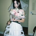 Nadezhda Tolokonnikova Instagram - 💍🔪🫀 american boy уеду с тобой @voguemagazine 📝: Sewing used to be a source of trauma for Pussy Riot’s Nadya Tolokonnikova, who was forced to stitch military and police uniforms while in a Russian penal colony. But she decided to reclaim the activity when she sewed Adidas stripes onto her now-husband John Caldwell’s suit jacket, for their wedding on 12 January. “Now I feel like I can sew again without being necessarily connected to the traumatic experience,” she says. “It broke the chain of trauma.” She wanted to create contrast between the “cute” side of her personality with the “gopnik” side. Tolokonnikova, who is vegan, juxtaposed her sweet look with an oversized black faux-leather Adidas jacket. She also wore a pair of velvet Doc Martens, though she changed into slides from—you guessed it—Adidas during the party. Tolokonnikova also included the Orthodox cross in her ceremony: on a necklace, garter belt, and even the vegan Napoleon cake covered in black icing, which she baked herself. “I’m almost trying to steal [the symbol] from the Orthodox Christianity, honestly, because they stole two years of my life,” she says. “I was accused—besides going against Putin—of religious hatred, which I didn’t have. But they still accused me of it. So I was like, Well, I’m just going to be using your symbol and reclaim it as my own.” She and Caldwell were married by Father Nathan Monk, who was excommunicated from the Russian Orthodox church for his support of the LGBTQ+ community, underneath a giant neon Orthodox cross. Photos: @marysergeevnaa Husbando: @vegsurfer Text: @hannahjacksuhn