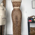 Natalia Fedner Instagram - Surprise!!! When @bloomingdales reached out to me about making a dress to celebrate the 50th anniversary of the Big Brown Bag - I was immediately on board! I wanted to bring my brand’s DNA to the project, while maintaining the integrity of the iconic Big Brown Bag kraft paper aesthetic. So I created a special chainmail made from actual Bloomingdale’s Big Brown Bags. This tiny paper chainmail, like my metal designs, is entirely hand made. The process starts by cutting the BBBs into 8.5 x 11” sheets, ironing them flat (yes, flashbacks to pressing paper patterns out at Parsons were had), then cutting the sheets into thousands of small strips using a hand held paper cutter (that I may have found tossed out on a street corner by my West Hollywood apartment…), and finally taping them together with little double sided tabs to create a honeycomb like pattern. I used this technique to create the skirt for the project, finishing it off with a Bloomingdales waistband (sourced from the side of the bag). The paper skirt is delicate, but because of the technique I developed for the project, it actually stretches quite a bit and allows a full range of movement! For the top, I wanted to design something a little more clean and simple that really focused on the theme. So I opted for a 90’s style bandeau top with the famous words front and center, integrating hand straps from actual bags to create shoulder straps for the top. By incorporating a few smart darts in the front and some corset work in the back, I was able to transition a Big Brown Bag into a Small Sleek Top. The overall silhouette of the look gives a wink to the 1950s, celebrating Bloomingdales lasting impact on fashion. Swipe through for a small taste of BTS - more to come! And yes model @lamekafox IS wearing a pair of our own chain earrings! Shoutout to @riowarner and @maya_adelle - this was a true labor of love that involved thousands of little movements - little cuts, little bits of tape - and these two rockstars made sure I got the project done in time by helping prep thousands of paper tabs for me. And thank you @p810km for being our fit model 🥰 Thank you @ela.ine.k @tatootsie for bringing me on!!