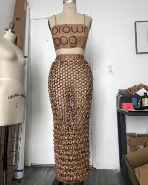Natalia Fedner Instagram - Surprise!!! When @bloomingdales reached out to me about making a dress to celebrate the 50th anniversary of the Big Brown Bag - I was immediately on board! I wanted to bring my brand’s DNA to the project, while maintaining the integrity of the iconic Big Brown Bag kraft paper aesthetic. So I created a special chainmail made from actual Bloomingdale’s Big Brown Bags. This tiny paper chainmail, like my metal designs, is entirely hand made. The process starts by cutting the BBBs into 8.5 x 11” sheets, ironing them flat (yes, flashbacks to pressing paper patterns out at Parsons were had), then cutting the sheets into thousands of small strips using a hand held paper cutter (that I may have found tossed out on a street corner by my West Hollywood apartment…), and finally taping them together with little double sided tabs to create a honeycomb like pattern. I used this technique to create the skirt for the project, finishing it off with a Bloomingdales waistband (sourced from the side of the bag). The paper skirt is delicate, but because of the technique I developed for the project, it actually stretches quite a bit and allows a full range of movement! For the top, I wanted to design something a little more clean and simple that really focused on the theme. So I opted for a 90’s style bandeau top with the famous words front and center, integrating hand straps from actual bags to create shoulder straps for the top. By incorporating a few smart darts in the front and some corset work in the back, I was able to transition a Big Brown Bag into a Small Sleek Top. The overall silhouette of the look gives a wink to the 1950s, celebrating Bloomingdales lasting impact on fashion. Swipe through for a small taste of BTS - more to come! And yes model @lamekafox IS wearing a pair of our own chain earrings! 

Shoutout to @riowarner and @maya_adelle - this was a true labor of love that involved thousands of little movements - little cuts, little bits of tape - and these two rockstars made sure I got the project done in time by helping prep thousands of paper tabs for me. And thank you @p810km for being our fit model 🥰 Thank you @ela.ine.k @tatootsie for bringing me on!!