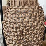 Natalia Fedner Instagram – Surprise!!! When @bloomingdales reached out to me about making a dress to celebrate the 50th anniversary of the Big Brown Bag – I was immediately on board! I wanted to bring my brand’s DNA to the project, while maintaining the integrity of the iconic Big Brown Bag kraft paper aesthetic. So I created a special chainmail made from actual Bloomingdale’s Big Brown Bags. This tiny paper chainmail, like my metal designs, is entirely hand made. The process starts by cutting the BBBs into 8.5 x 11” sheets, ironing them flat (yes, flashbacks to pressing paper patterns out at Parsons were had), then cutting the sheets into thousands of small strips using a hand held paper cutter (that I may have found tossed out on a street corner by my West Hollywood apartment…), and finally taping them together with little double sided tabs to create a honeycomb like pattern. I used this technique to create the skirt for the project, finishing it off with a Bloomingdales waistband (sourced from the side of the bag). The paper skirt is delicate, but because of the technique I developed for the project, it actually stretches quite a bit and allows a full range of movement! For the top, I wanted to design something a little more clean and simple that really focused on the theme. So I opted for a 90’s style bandeau top with the famous words front and center, integrating hand straps from actual bags to create shoulder straps for the top. By incorporating a few smart darts in the front and some corset work in the back, I was able to transition a Big Brown Bag into a Small Sleek Top. The overall silhouette of the look gives a wink to the 1950s, celebrating Bloomingdales lasting impact on fashion. Swipe through for a small taste of BTS – more to come! And yes model @lamekafox IS wearing a pair of our own chain earrings!
Shoutout to @riowarner and @maya_adelle – this was a true labor of love that involved thousands of little movements – little cuts, little bits of tape – and these two rockstars made sure I got the project done in time by helping prep thousands of paper tabs for me. And thank you @p810km for being our fit model 🥰 Thank you @ela.ine.k @tatootsie for bringing me on!!
