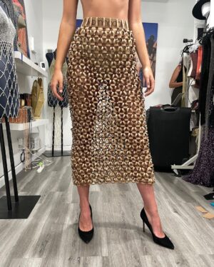 Natalia Fedner Instagram - Surprise!!! When @bloomingdales reached out to me about making a dress to celebrate the 50th anniversary of the Big Brown Bag - I was immediately on board! I wanted to bring my brand’s DNA to the project, while maintaining the integrity of the iconic Big Brown Bag kraft paper aesthetic. So I created a special chainmail made from actual Bloomingdale’s Big Brown Bags. This tiny paper chainmail, like my metal designs, is entirely hand made. The process starts by cutting the BBBs into 8.5 x 11” sheets, ironing them flat (yes, flashbacks to pressing paper patterns out at Parsons were had), then cutting the sheets into thousands of small strips using a hand held paper cutter (that I may have found tossed out on a street corner by my West Hollywood apartment…), and finally taping them together with little double sided tabs to create a honeycomb like pattern. I used this technique to create the skirt for the project, finishing it off with a Bloomingdales waistband (sourced from the side of the bag). The paper skirt is delicate, but because of the technique I developed for the project, it actually stretches quite a bit and allows a full range of movement! For the top, I wanted to design something a little more clean and simple that really focused on the theme. So I opted for a 90’s style bandeau top with the famous words front and center, integrating hand straps from actual bags to create shoulder straps for the top. By incorporating a few smart darts in the front and some corset work in the back, I was able to transition a Big Brown Bag into a Small Sleek Top. The overall silhouette of the look gives a wink to the 1950s, celebrating Bloomingdales lasting impact on fashion. Swipe through for a small taste of BTS - more to come! And yes model @lamekafox IS wearing a pair of our own chain earrings! 

Shoutout to @riowarner and @maya_adelle - this was a true labor of love that involved thousands of little movements - little cuts, little bits of tape - and these two rockstars made sure I got the project done in time by helping prep thousands of paper tabs for me. And thank you @p810km for being our fit model 🥰 Thank you @ela.ine.k @tatootsie for bringing me on!!