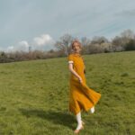 Rebecca Flint Instagram – Spring’s first light filling the pages with shimmering delight ☀️ 

Feeling very little women, in my @sondeflor classic short sleeve dress in marigold 🌻 
 
made from 100% locally sourced Lithuanian linen and free shipping right now 😊

#thisjaneaustenlife #ofwhimsicalmoments #fairycore #cottagefairy #asecondofwhimsey #wherefairiesdwell #theheartofslowliving #softcore #coquetteaesthetic #parisiennegirl #thatvelvetfeeling #dreaminginpictures #amomentofwonder #ofquietmoments #whimsicalwonderfulwild #meadowcore #gardencore #warmcore #vintagecore #aseasonalshift #embracingtheseasons #quietchaotics #naturecore #lafemmeparisienne #monlook #onparledemode #romanticstyle #softgirlaesthetic #fashionhistory #springoutfitideas