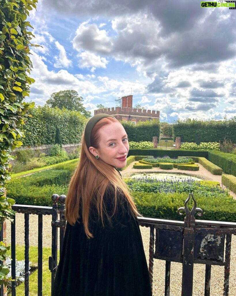 Rebecca Flint Instagram - if you can’t wear a cape in hampton court palace i’m not sure where you can 🌹? I have always wanted to see this incredible tudor palace for myself and I was so excited to have the chance! they had live cooking demonstrations inside the original kitchens, and we saw so many amazing tapestries and paintings… incredible day to visit! the puff headband trend always reminds me of the French Hood so I had to wear this army green one, along with this spectacular velvet and silk cape picked up from @classiccarbootsale in the spring! My dress is vintage from Japan, and my bag is @aspinaloflondon. The shoes are @empressaustralia 🔍 Not forgetting my B necklace as an homage to Anne 🅱❤ Hampton Court Palace