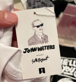 Seth Bogart Instagram - What an honor to design 3 collections of merchandise for the great new John Waters “Pope of Trash” show at @academymuseum ‼️
Seeing my art all huge on 2 walls at the end of the exhibit blew my mind. 

Love this pic @greggormanphoto took of John in front of my drawing of him. Just wait til you see the whole bathroom collection & the Divine/Pink Flamingos collection - both of those will be dropping sometime soon. Go see the show !!!